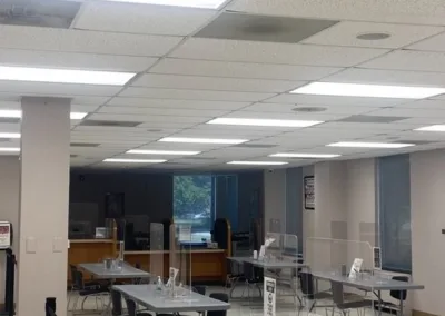 Interior of a public office with tables set up with clear partitions, chairs, and a caution sign, indicating social distancing measures.